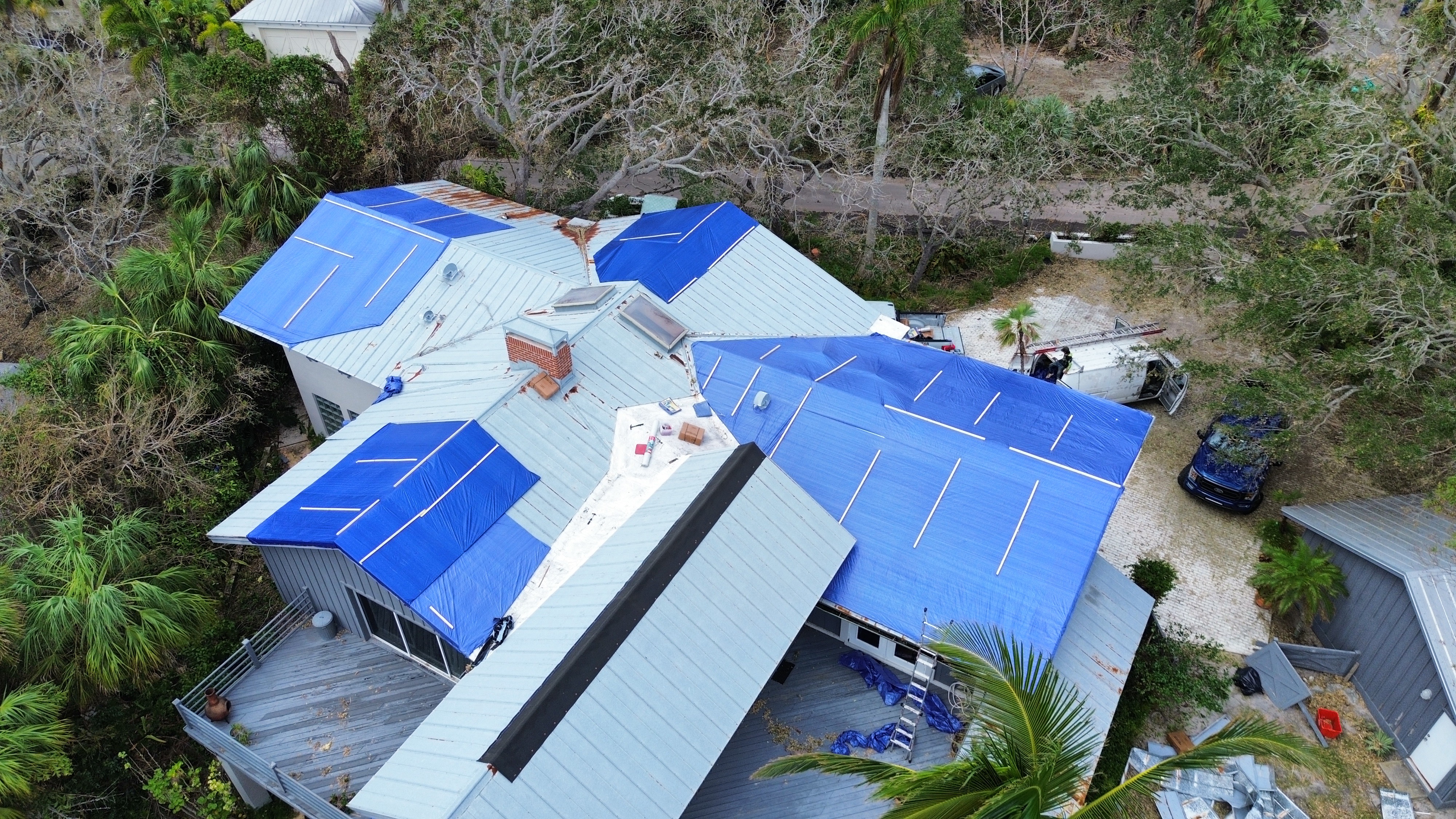 Emergency blue tarps installed on metal roof after storm damage by Horizon Commercial Roofing